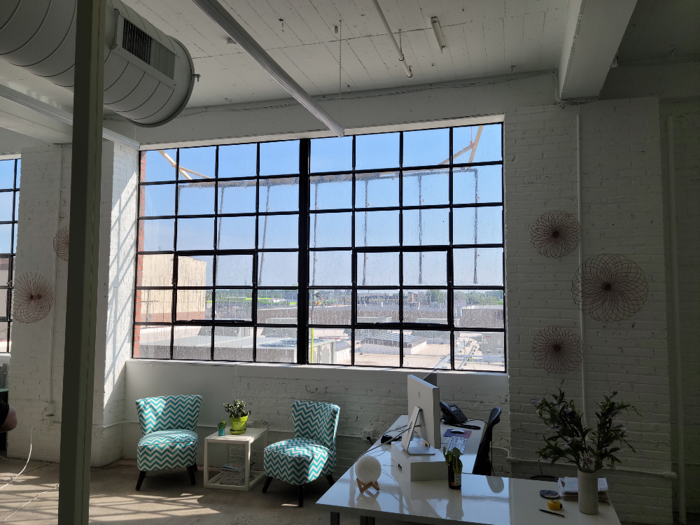 This image shows a bright, spacious office with a large industrial-style window that lets in plenty of natural light. Fenestration Testing is taking place to improve the thermal performance of the windows.